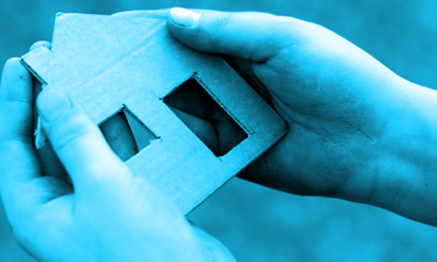 A pair of hands holding a small house