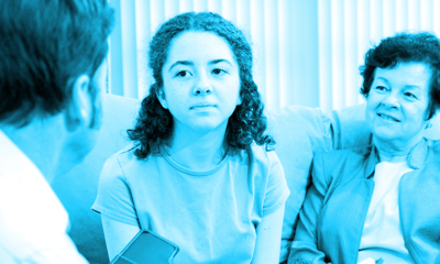 A woman sitting next to an older woman chatting to a man