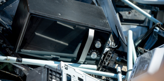 A microwave and other waste electrical appliances in a container at a recycling centre.