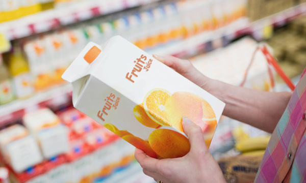 A lady holding a fruit juice carton.