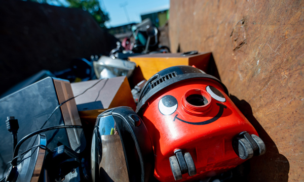 A vacuum cleaner, kettle and other waste electrical items in a container at a recycling centre.