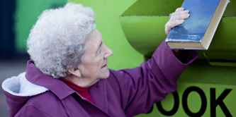 Lady placing a book in a book recycling container.