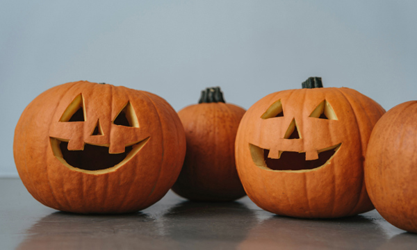 4 pumpkins in a row - 2 carved with faces, 2 uncarved.