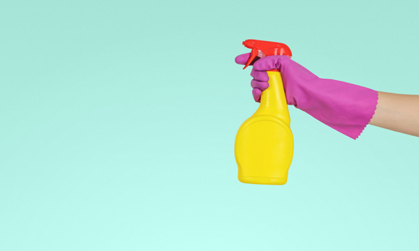 A spray bottle being held by a person wearing a rubber glove.