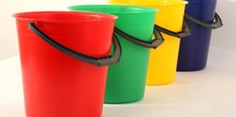 Red, green, yellow and blue plastic buckets in a line