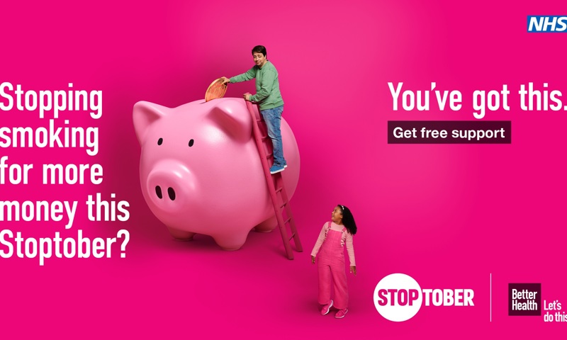 Man climbs a pink ladder and puts a giant coin into a giant piggy bank.