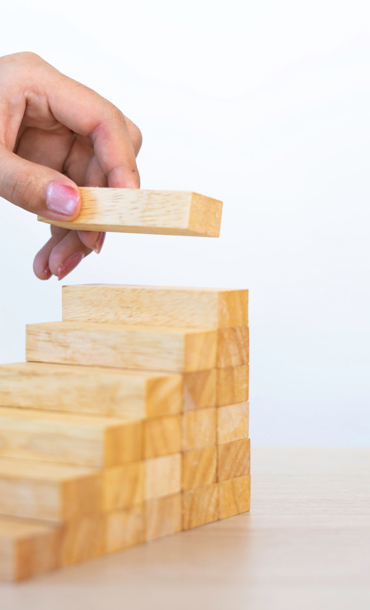 Wooden blocks stacked to look like steps with a the last one to put in place at the top.