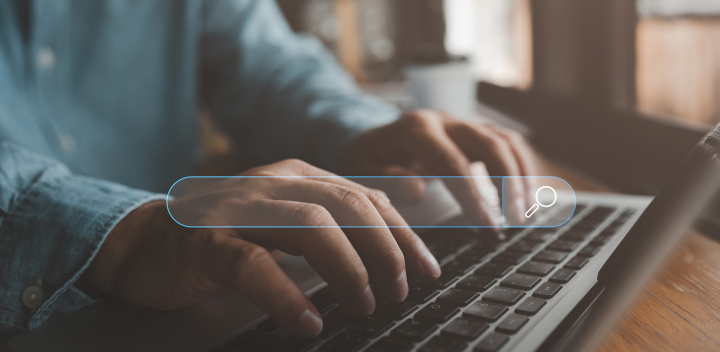 nojs A person's hands typing on a laptop keyboard with a search field overlaying the image to signify a job search.