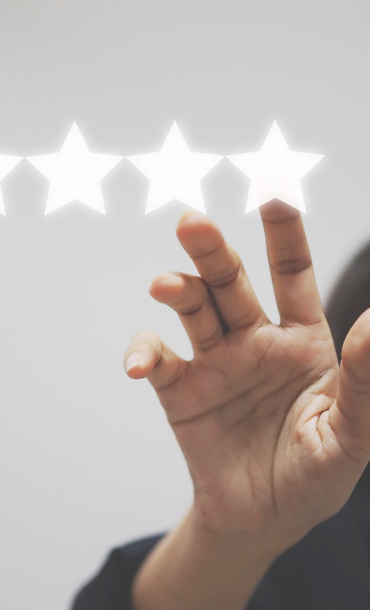 A woman holding up her hand and touching the fifth of five stars in a row.