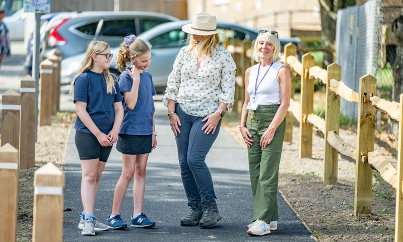 Perusing the footway improvements and new crossing points near Barns Green Primary School: from left, two of the school's pupils with County Council Cabinet Member for Highways and Transport Joy Dennis and Headteacher Tracey Newbold