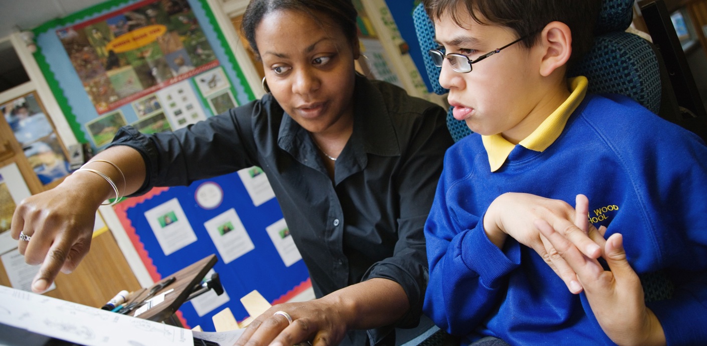 nojs Teacher helping disabled young person.