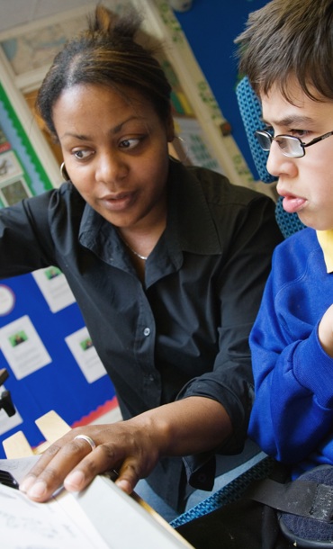 Teacher helping disabled young person.
