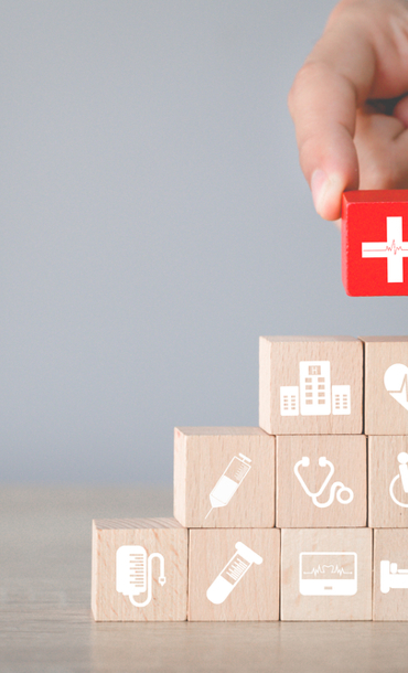 Hand arranging wood block stacking with healthcare icon.