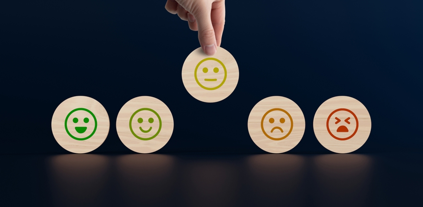 nojs Wooden discs with icons of faces from happy to sad, a hand picks up a disc with an icon. The concept of evaluating, indicating the degree of satisfaction with the transaction.
