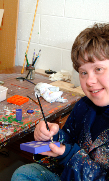 Boy with special needs smiling and painting.