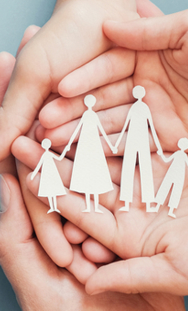 Hands holding paper cut-outs of a family