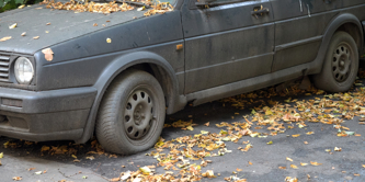 An old black car with a flat tyre.
