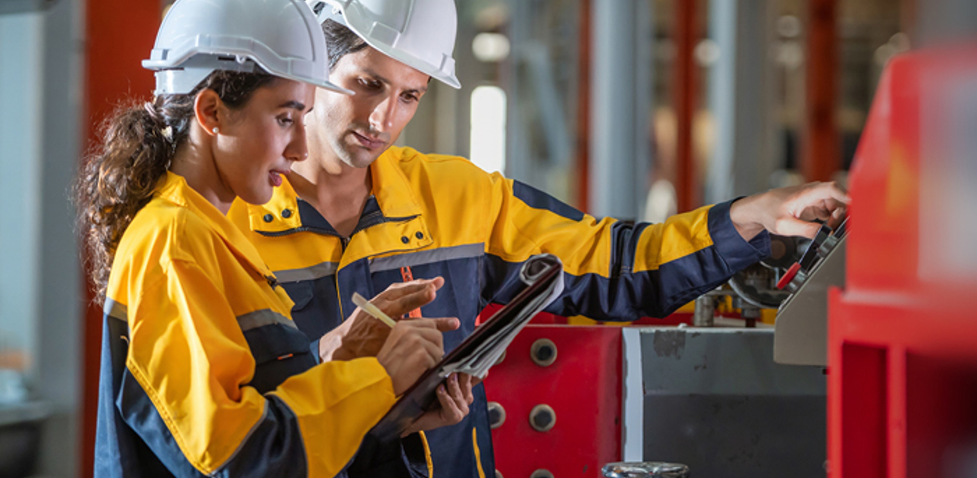 nojs A man and woman in work gear and hard hats looking at a checklist.