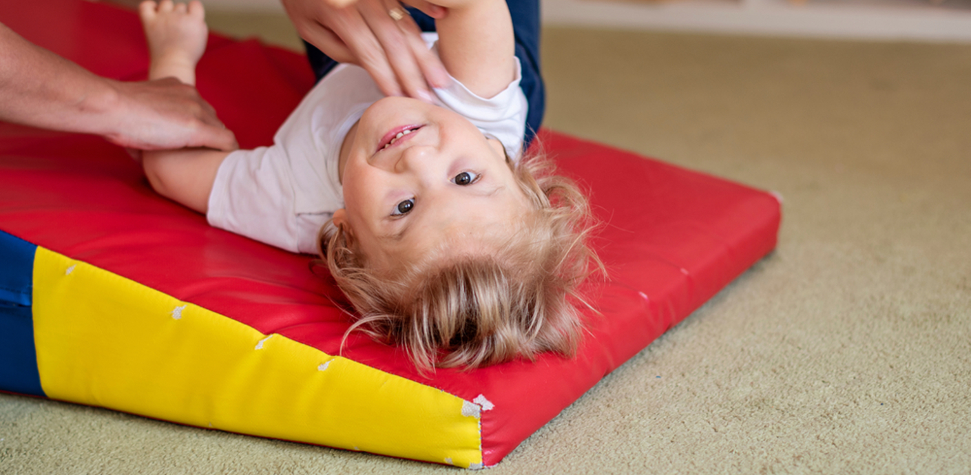nojs Child on a foam mat supported by adult hands