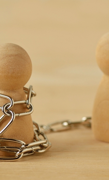 Two wooden pawns, one wrapped in chains