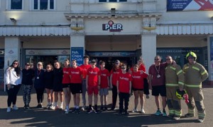 Fire Cadets, staff, and volunteers standing in front of the pier