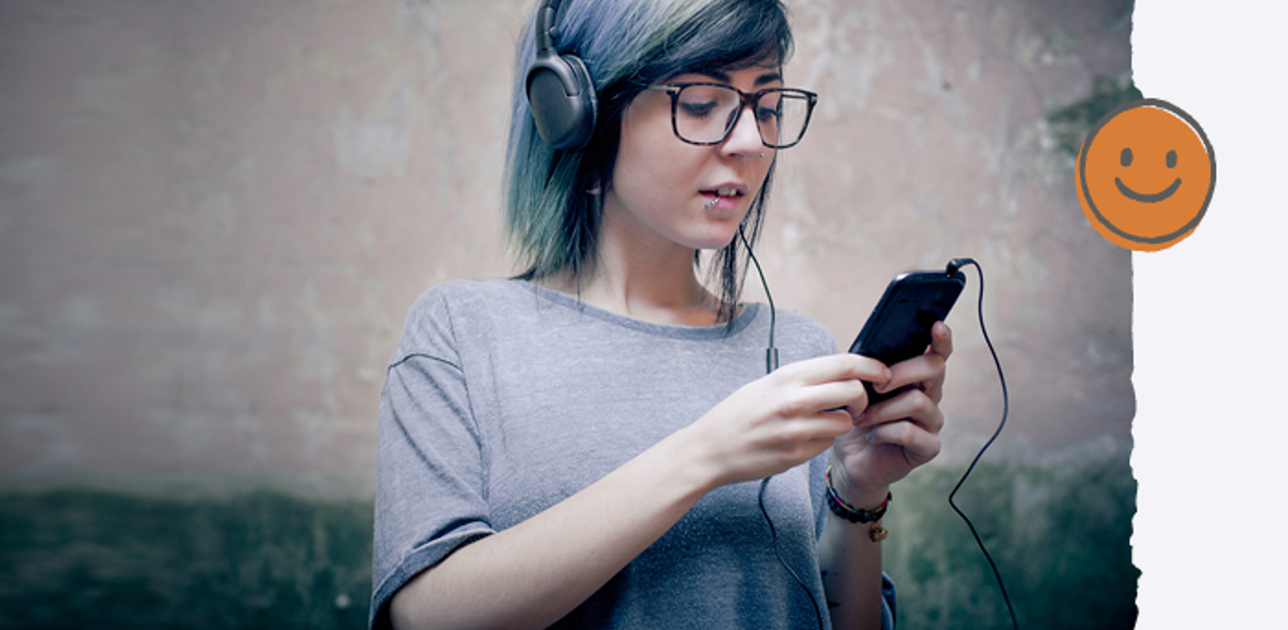 nojs A young woman with headphones on wired to her mobile phone she's holding.